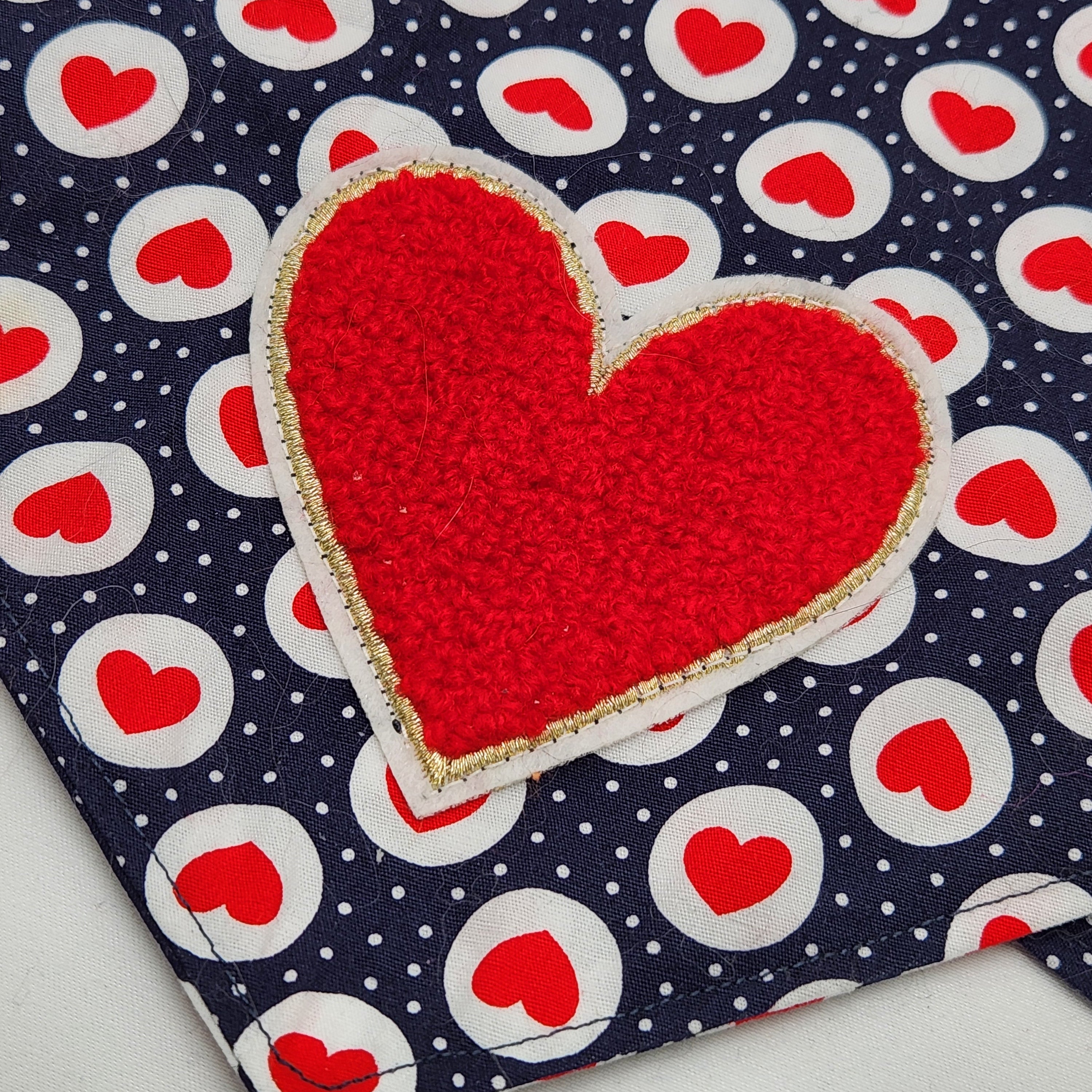 Red heart-shaped patch on a fabric with red heart pattern