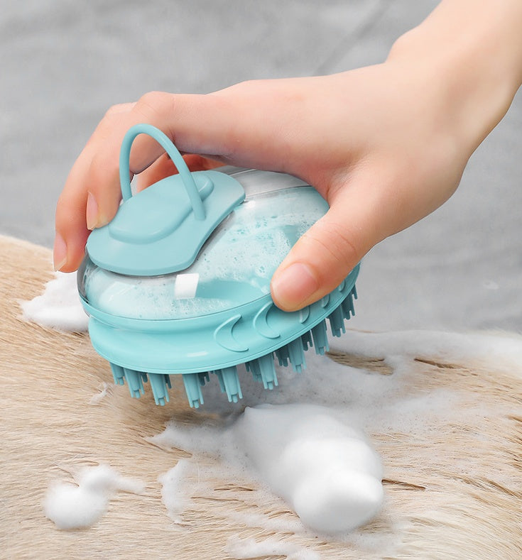 Hand holding a blue silicone pet scrubber with soap suds on a wooden surface
