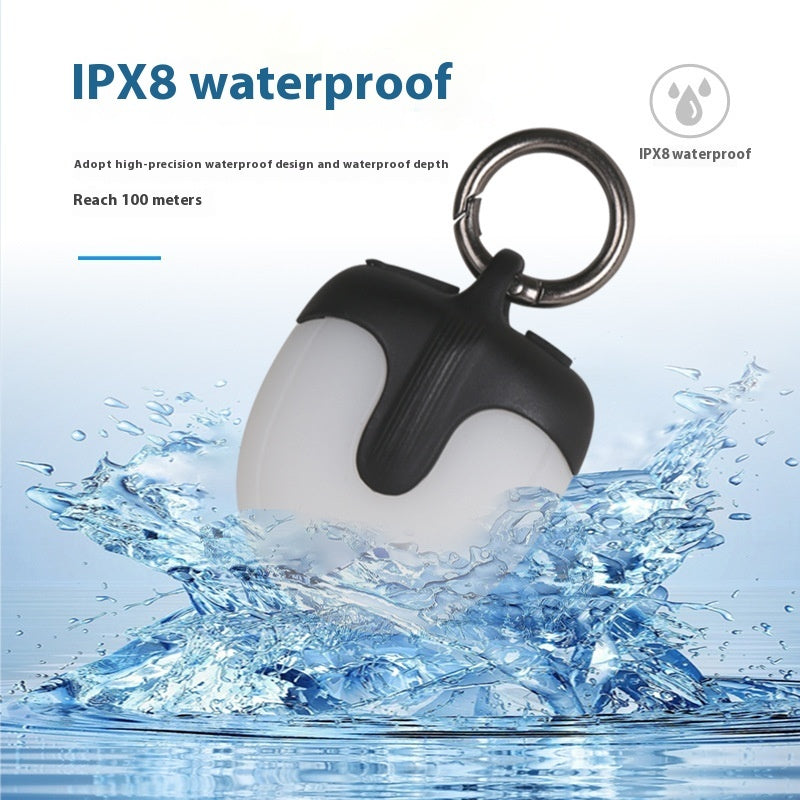 Black and white waterproof dog led light with keychain, surrounded by water, on a light blue background.