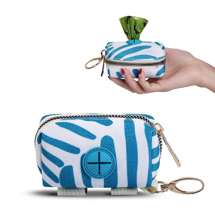 Blue and white patterned poop bag dispenser pouch with a keychain held by a hand on a white background
