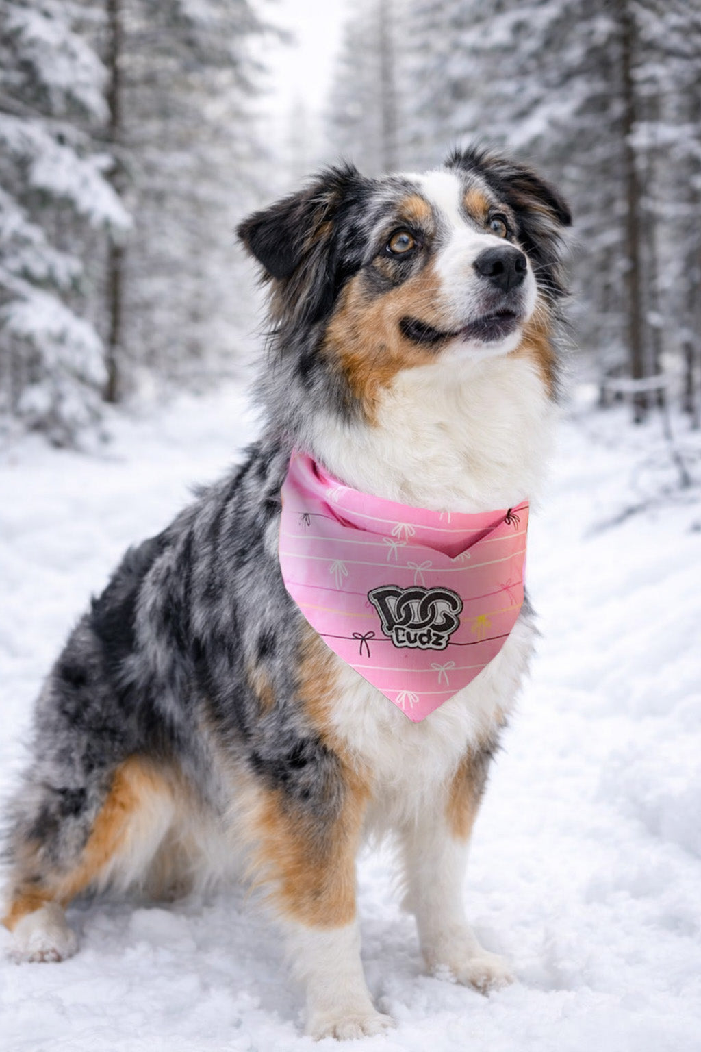 Dog wearing a pink bandana with a logo in a snowy forest