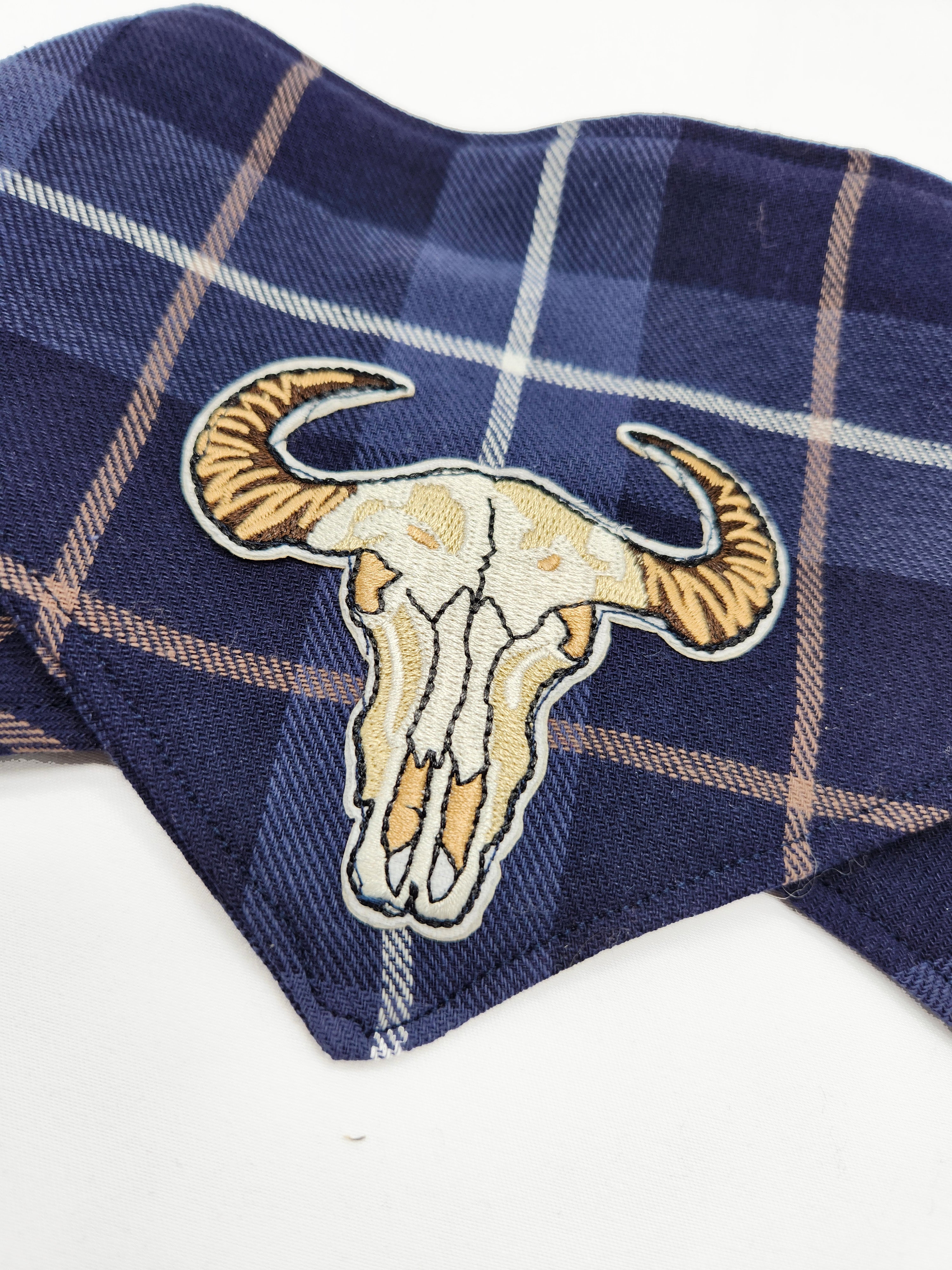 Navy plaid fabric with a bull skull patch on a white background