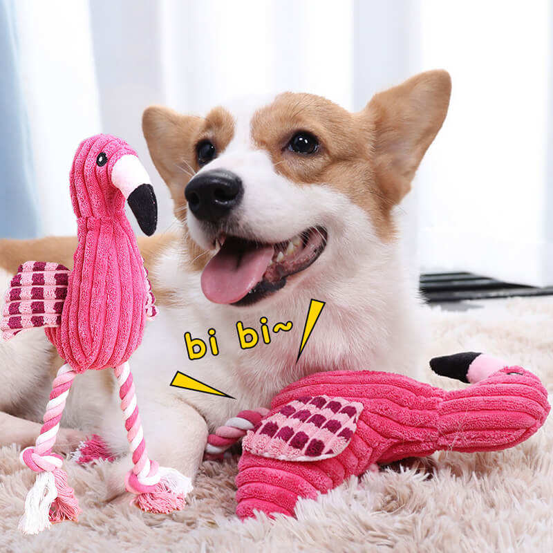 Dog playing with a pink flamingo toy on a soft surface