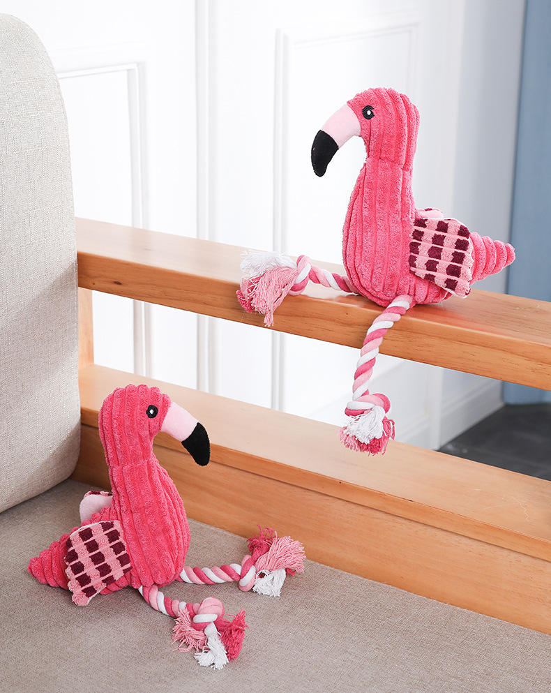 Two pink flamingo toys with rope on a wooden surface.