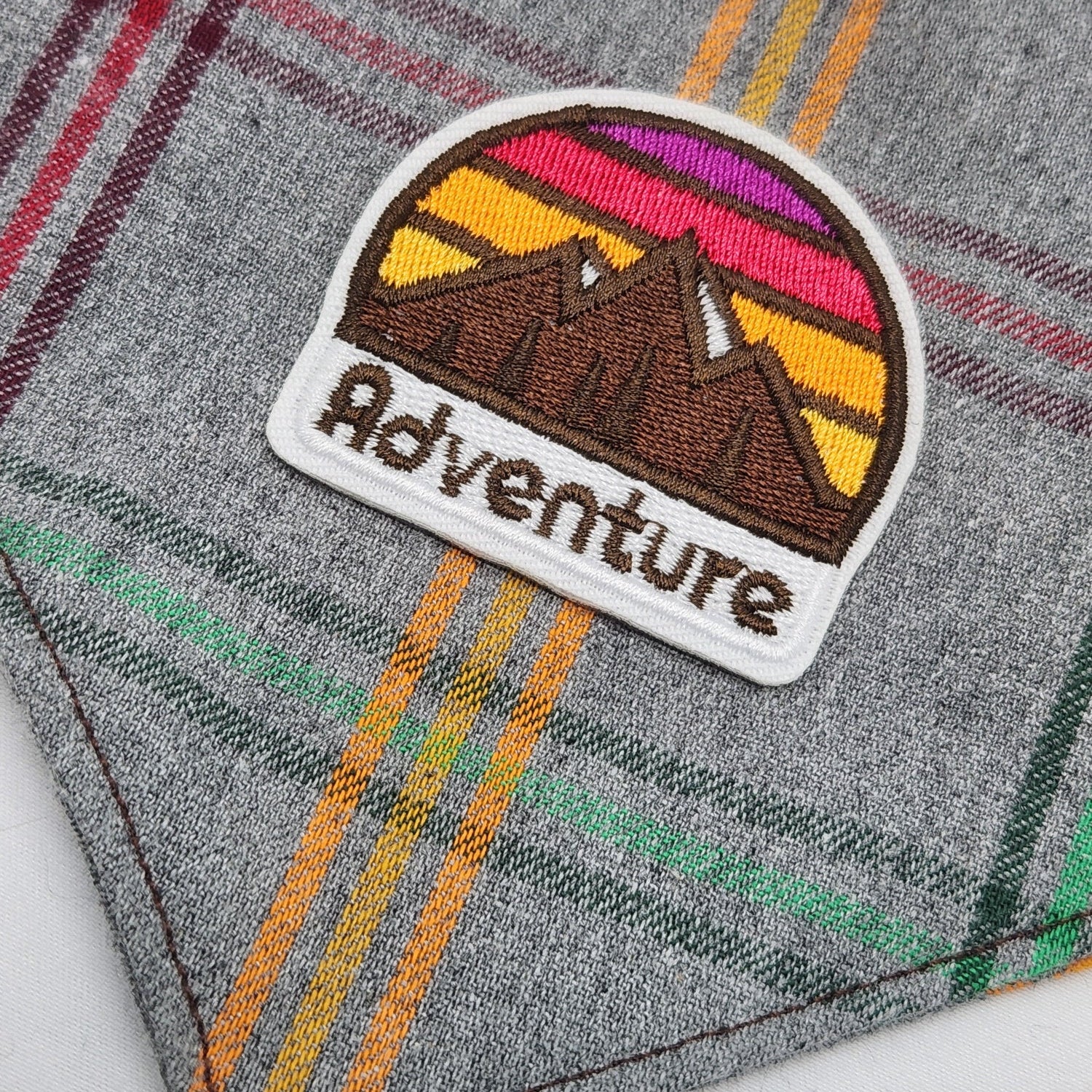Plaid bandana with a 'Adventure' patch featuring a colorful design.