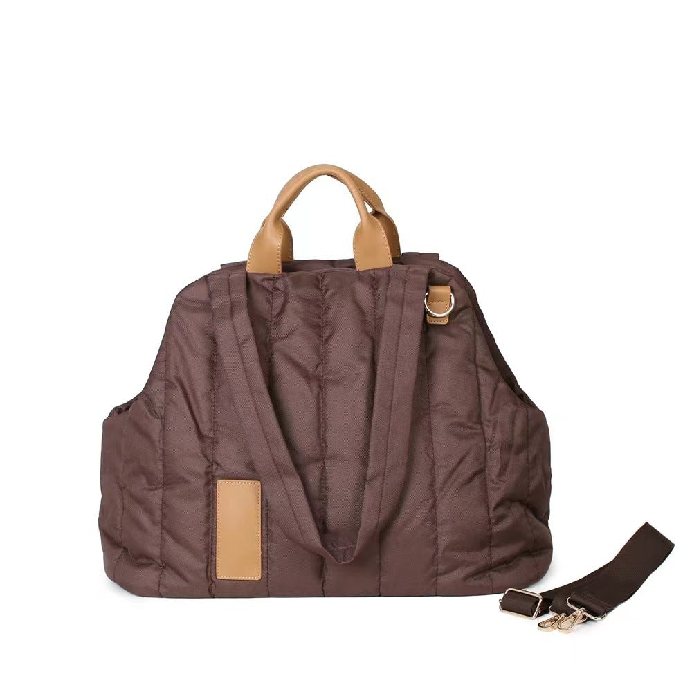 Brown pet carrier with tan leather straps and handle on a white background