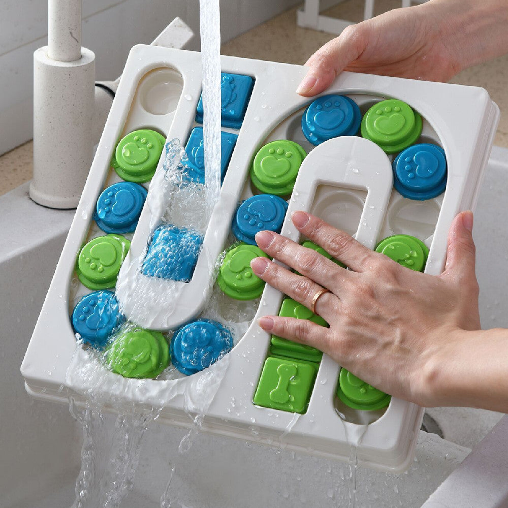 Person washing a white tray with blue and green circular molds under running water.