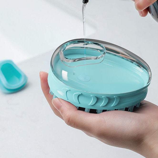 Turquoise silicone pet bath brush being rinsed under running water with a hand holding it.