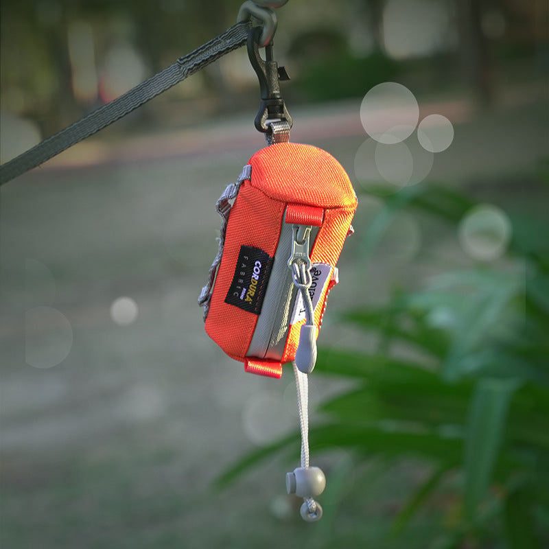 Orange poop bag dispenser with carabiner on a blurred natural background