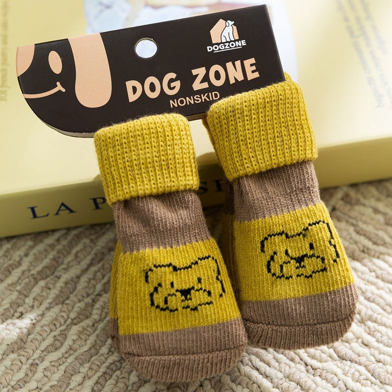 Pair of yellow and brown dog socks with a 'Dog Zone' label on a textured surface.