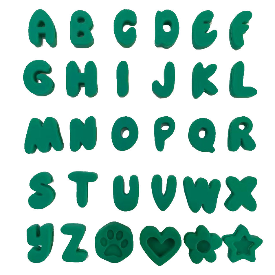 Green alphabet cookie cutters and stamps arranged in a grid on a white background, including letters A through Z, a paw print, a heart, a flower, and a star.