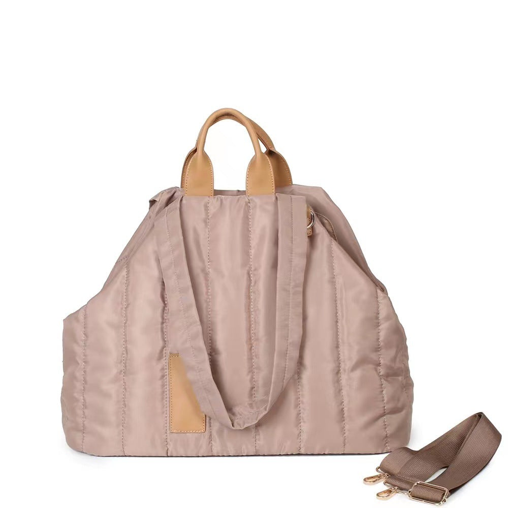 Beige tote bag with brown handles and strap on a white background